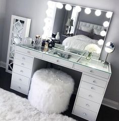 a bedroom with a vanity, mirror and stool on the floor in front of it