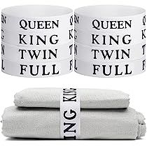 three white towels stacked on top of each other with black letters in the middle and one is