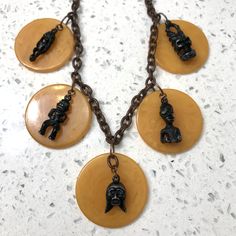 A tikitastic necklace made from 1930's-40's marbelized butterscotch tested bakelite (Catalin) chips with very solid true vintage cast metal tiki gods ☀️🗿☀️🗿☀️🗿☀️ One-off--Repurposed on new plastic chain: I always felt these charms were too awesome to be on a boring skinny black cord in bracelet form.  Most of the tiki faces still have the green sparkly eyes. The figuines have booties 🍑 Please check out the other jewelry in my collection, and message me if you have any specific preferences--I Tiki Faces, Sparkly Eyes, Vintage Tiki, Metal Casting, True Vintage, Made By Me, Kitsch, Vintage Metal, Charm Necklace