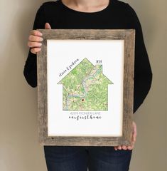 a woman holding up a framed map with the words, home is where you are