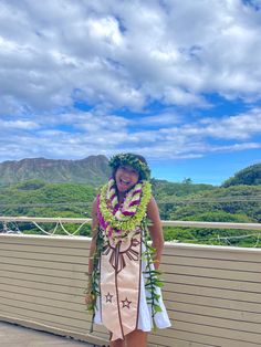 a woman standing on top of a roof wearing a lei