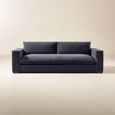 a black couch sitting on top of a floor next to a white wall with a light colored background