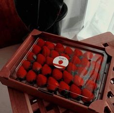 a box filled with lots of red fruit on top of a wooden table