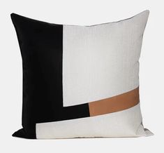 a black and white pillow with an orange strip on it's side, sitting against a gray background