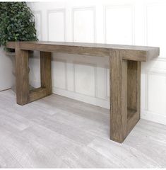 a wooden bench sitting on top of a hard wood floor next to a potted plant