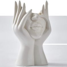 a white ceramic sculpture holding its hands in the air