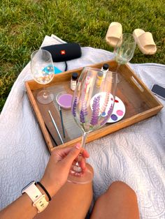 a person holding a wine glass in front of a tray with other items on it