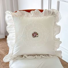 a white pillow with ruffled edges on a chair