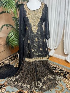 Ready to wear can ship same business day. Color     Black and gold  Fabric    shirt, dupatta (chiffon)                 Inner banarsi jamavar and also a soft                  Layer underneath                  Sharara fabric Banarsi chiffon  Embroidery details  Total handmade adda work Kora, Dabka, Stones, Pearls The fabric used in this dress is very high quality. Embroidery is very elegant and neat and gives designer dress. Very high quality nicely stitched stylish sharara suit. Size Large  Shoulder 17 Chest 22 Waist 21 Hips 23 Shirt length 35 Sharara length 44 This dress is available in size  large  ready to wear and  can ship immediately. if you need same dress in other sizes  can be made to your size contact me 818-687-2408  for your customize size. Thanks Gold Floor-length Kurta With Sheer Dupatta, Formal Semi-stitched Jamawar Dupatta, Gold Salwar Kameez With Sheer Dupatta Floor-length, Elegant Georgette Saree With Dabka, Gold Floor-length Salwar Kameez With Sheer Dupatta, Gold Floor-length Designer Kurta, Gold Designer Floor-length Kurta, Designer Gold Floor-length Kurta, Organza Kurta With Pallu For Wedding