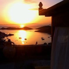 the sun is setting over an ocean with boats