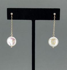 Add a touch of elegance to any outfit with our Coin Pearl Dangle Earrings. Available in 14k gold filled or sterling silver, these earrings are nickel-free and hypoallergenic, making them ideal for sensitive ears. Featuring a stunning 12mm (0.5 inch) coin pearl with gorgeous luster, these earrings dangle gracefully from a delicate chain attached to a ball post. With a total drop length of 1.5 inches, they are perfect for any dressy occasion, including weddings, bridal jewelry, and for bridesmaids. Each pair of earrings arrives beautifully packaged in a gift box. Material Options: 14k gold filled or sterling silver Hypoallergenic: Nickel-free, perfect for sensitive ears Elegant Design: 12mm (0.5 inch) coin pearl with beautiful luster Graceful Drop: 1.5 inches total length, with the pearl dan White Drop Earrings For Formal Occasion, Pearl White Dangle Earrings For Pierced Ears, Pearl White Dangle Earrings, Pearl White Dangle Earrings For Formal Occasions, Classic Round Linear Earrings For Gifts, Classic Round Linear Earrings Gift, White Gold Long Drop Earrings For Anniversary, Clip-on Dangle Earrings In Yellow Gold, Yellow Gold Clip-on Dangle Jewelry