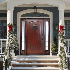 a red front door with two wreaths on the steps next to it and christmas decorations