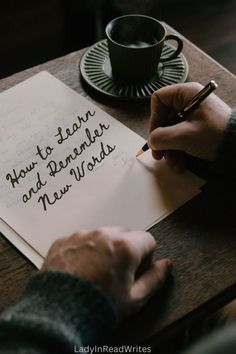 someone writing on a piece of paper next to a cup of coffee