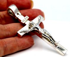 a person holding a silver cross in their hand