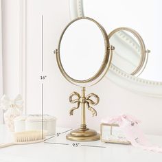 a mirror sitting on top of a white table next to a brush and cupcake