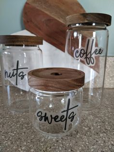 three glass jars with words on them sitting on a counter top next to a cutting board