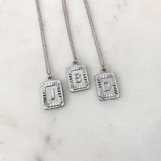 Silver Initial Letter Pendant Necklace Trendy Silver Jewelry With Initials, Silver Metal Initial Pendant Necklace, Rectangular Stainless Steel Necklaces, Personalized Rectangular Metal Jewelry, Trendy Silver Square Pendant Jewelry, Trendy Silver Monogram Necklace, Silver Rectangular Tarnish-resistant Jewelry, Silver Stainless Steel Rectangular Necklace, Silver Rectangular Stainless Steel Necklace