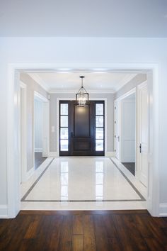 an empty room with white walls and wood floors, light fixture hanging from the ceiling