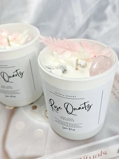 two ice creams sitting on top of a white plate with pink flowers in them