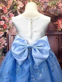 the dress is blue and has a large bow at the waist, along with flowers