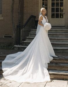 a woman in a wedding dress is standing on the steps with her bouquet and looking at the camera