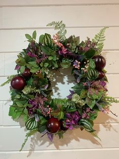 a wreath with apples and greenery hanging on a wall