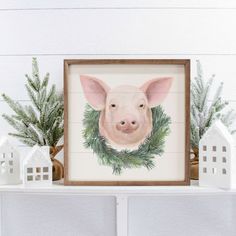 a painting of a pig is displayed on a mantel with christmas greenery and small white houses