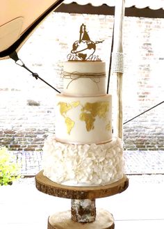 a three tiered cake sitting on top of a wooden stand with a map on it