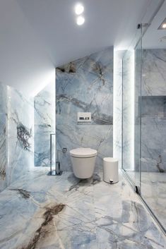 a bathroom with marble walls and flooring next to a glass enclosed shower stall area