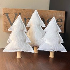 three small white christmas trees sitting on top of a wooden table