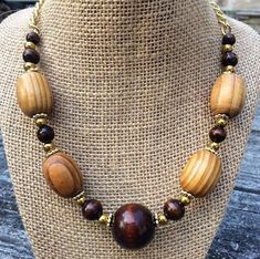 This elegant, one of a kind necklace is made up of real wood- stained light and dark - and painted gold beads. The beads are all tied securely to a gold chain which fastens easily behind the neck with a toggle clasp. The necklace measures around 18 inches long. Wood Beads Necklace Ideas, Adjustable Gold Beaded Necklaces With Wooden Beads, Adjustable Gold Beaded Necklace With Wooden Beads, Gold Beaded Necklaces With Wooden Beads, Adjustable Gold Necklace With Wooden Beads, Gold Beaded Necklace With Wooden Beads, Wooden Beaded Jewelry With Round Beads, Beaded Natural Wood Jewelry, Natural Wood Beaded Jewelry