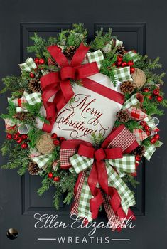 a christmas wreath on the front door with red and green ribbon, pine cones, evergreens and berries