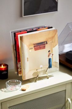 an open album sitting on top of a table next to a candle and some pictures