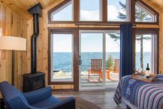 a bedroom with a bed, chair and fire place in it next to the ocean