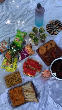 an assortment of snacks are laid out on a sheet with water bottle and other items