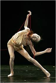 a man in white shirt and tan pants on stage with one leg bent over the other