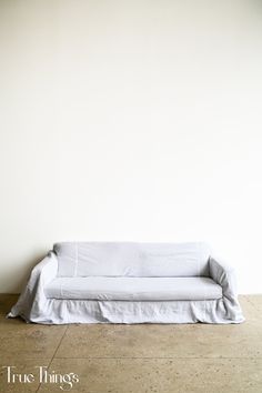 a white couch sitting on top of a hard wood floor next to a white wall