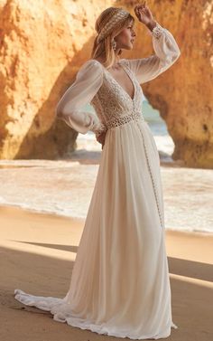 a woman standing on top of a beach next to the ocean wearing a white dress