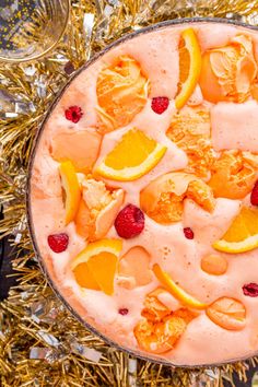 a dessert with oranges, raspberries and other fruit on top of tinsel