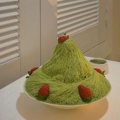 there is a green cake with strawberries on it