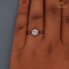 a woman's hand with a diamond and blue sapphire engagement ring on her finger