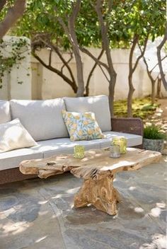 a couch sitting on top of a stone floor next to a tree filled backyard area