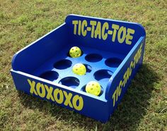 a blue tic - tac - toe game sitting in the grass with yellow balls