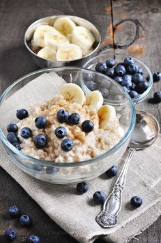 oatmeal with blueberries and banana slices in glass bowl on wooden table