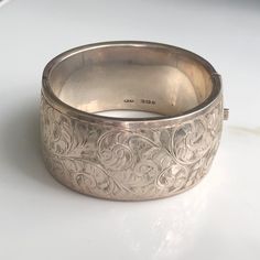 A vintage silver bangle with an ornate floral style. CONDITION: Wear consistent with age and use. Please see photos for more detail. HALLMARKED SILVER, ASSAYED IN BIRMINGHAM  APPROX. INTERNAL SIZE: BANGLE WIDTH: 31mm WEIGHT: 52.1g INTERNAL DIAMETER: 57mm x 52mm (CZ) Classic Etched Bangle For Wedding, Victorian Antique Silver Bracelets For Wedding, Classic Etched Wedding Bangle, Heirloom Etched Bangle For Wedding, Antique Silver Cuff Bangle Bracelet, Ornate Engraved Bangle For Formal Occasions, Heirloom Cuff Bracelet With Intricate Design For Formal Occasions, Vintage Bangle Bracelets For Wedding, Vintage Engraved Bracelets For Wedding