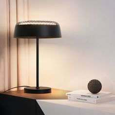 a black lamp sitting on top of a wooden table next to a white book shelf