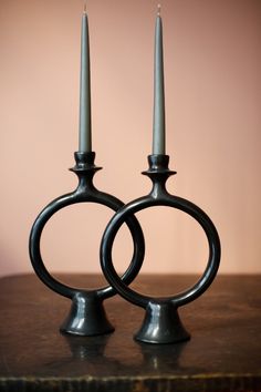 two metal candlesticks sitting on top of a wooden table