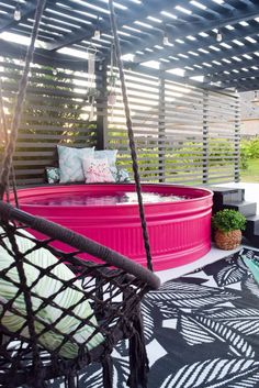 a large pink tub sitting on top of a black and white floor next to a swimming pool