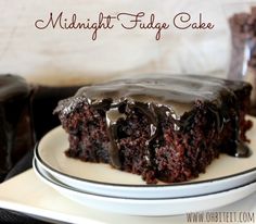 a piece of chocolate cake on a plate with the words midnight fudge cake above it