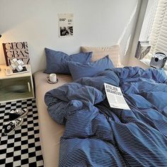 a bed sitting next to a window covered in blue and white sheets on top of a black and white checkered floor